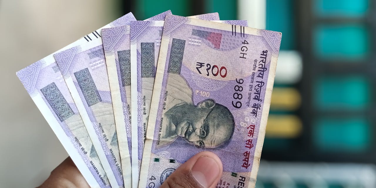services-04 Close-up view of holding Indian 100 rupee banknotes, showcasing currency details and design.